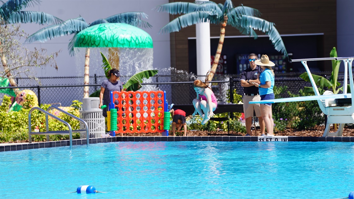 Girl jumping into a large pool, cannon ball style