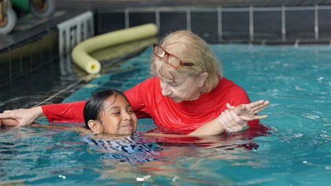 a swim instructor showing a student how to swim