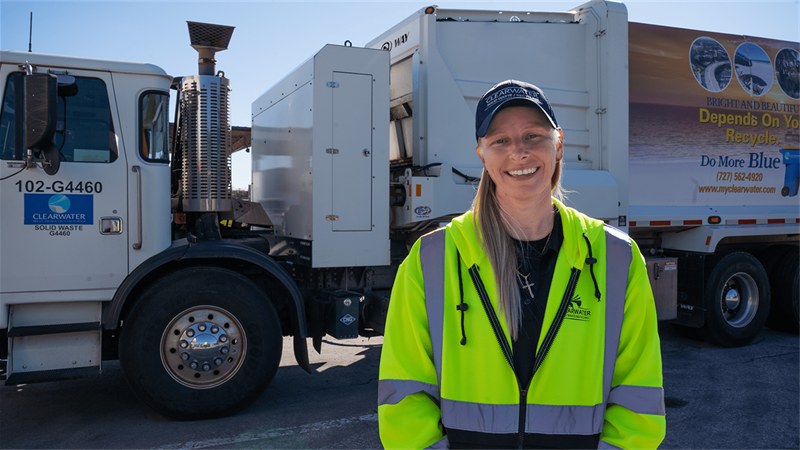 This is a woman who is smiling and standing next to a Clearwater solid waste truck