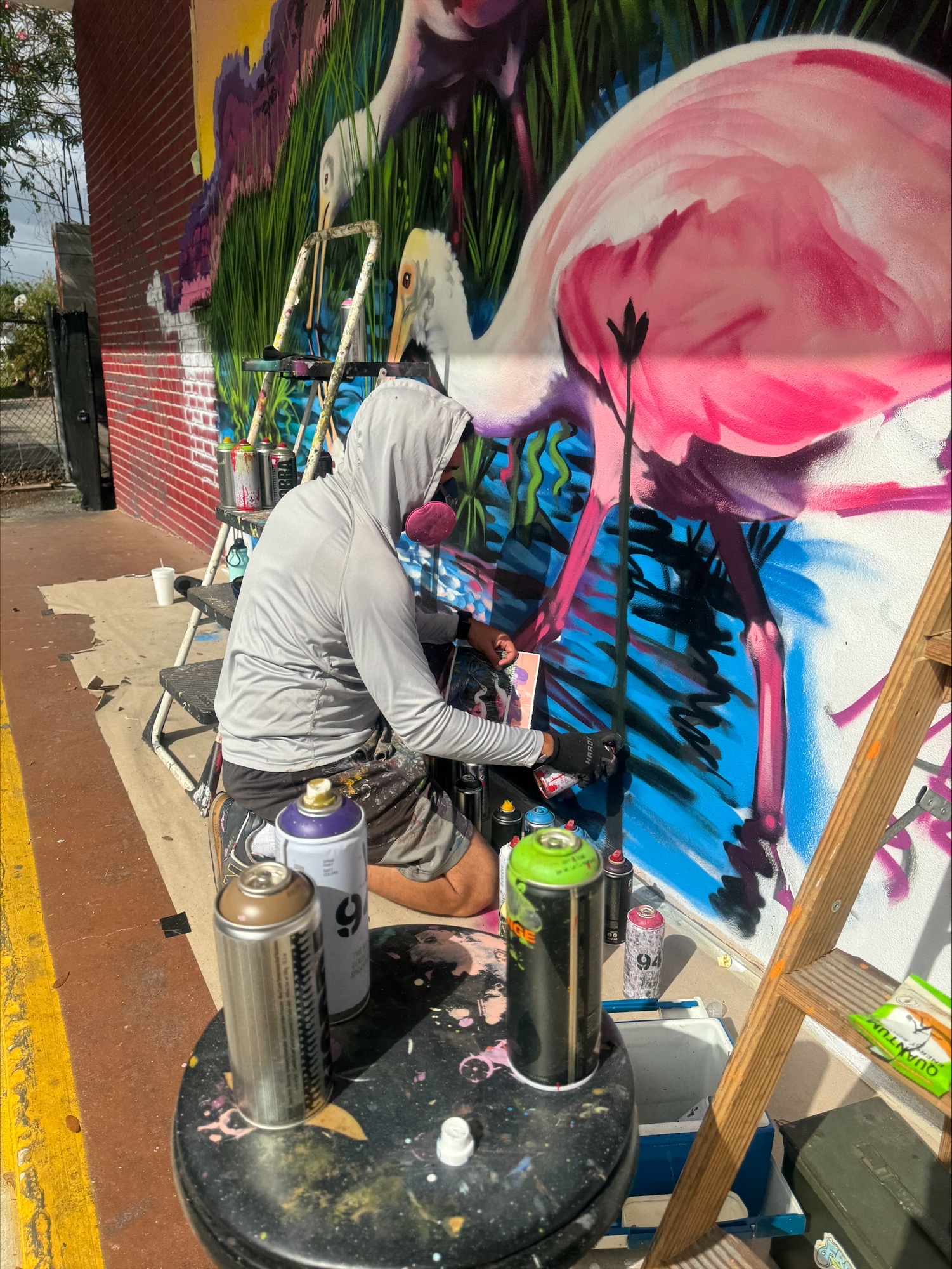 artist painting pink flamingo on mural