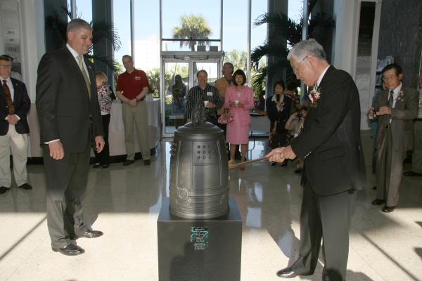 Japanese representative from Nagano Japan striking the large bell presented to the City of Clearwater Florida.