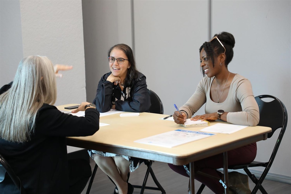 Three women sitting at a table having a discussion.