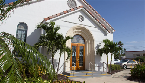Entrance to the chapel with palm trees on either side of the door.