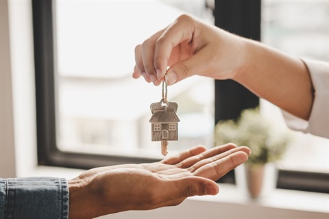 person giving a house key to another person