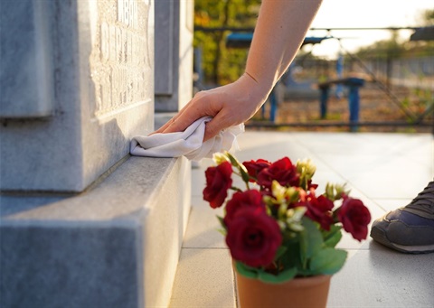 Person cleaning a headstone.