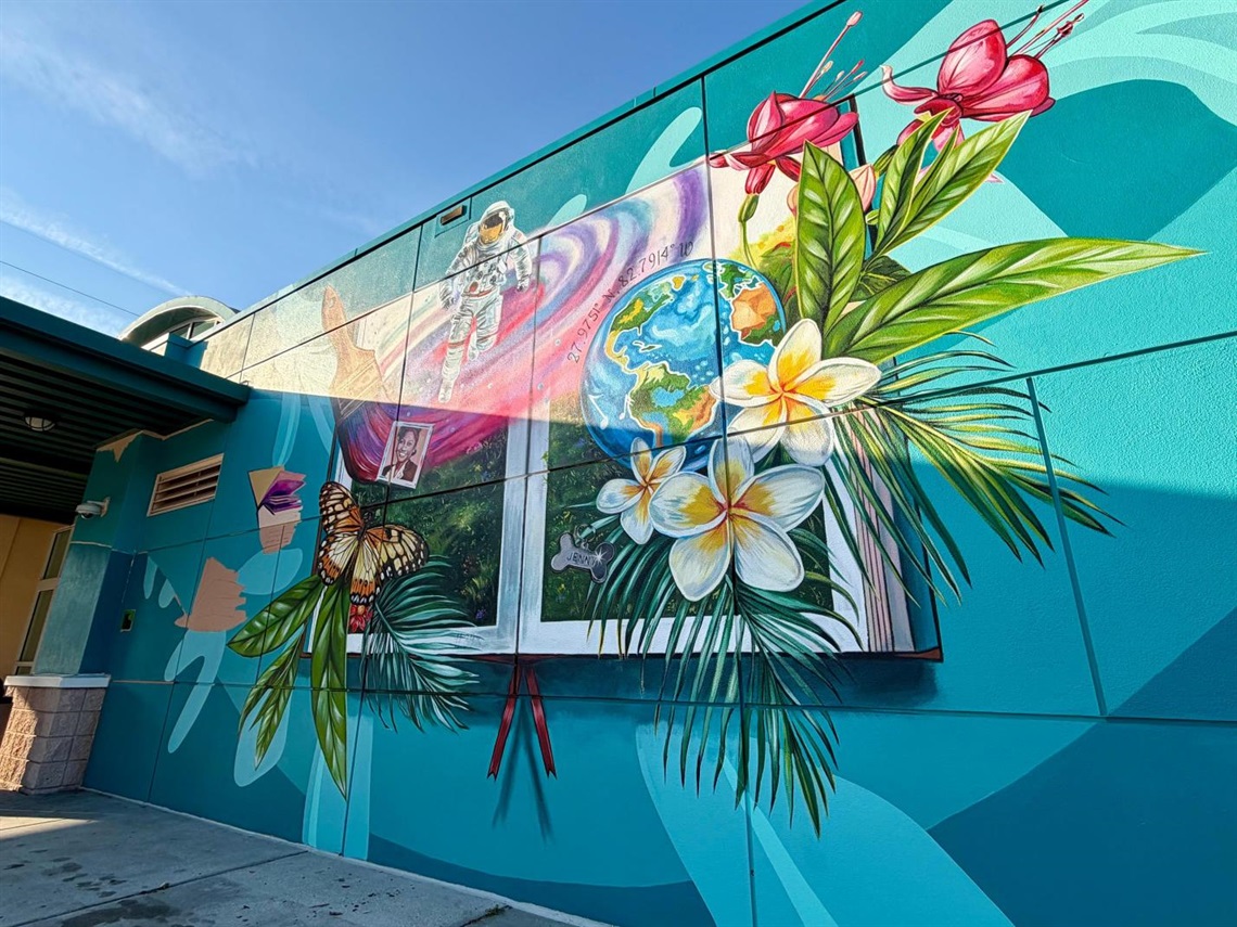 Large exterior wall mural with paint brush, astronaut, butterfly and flowers. 
