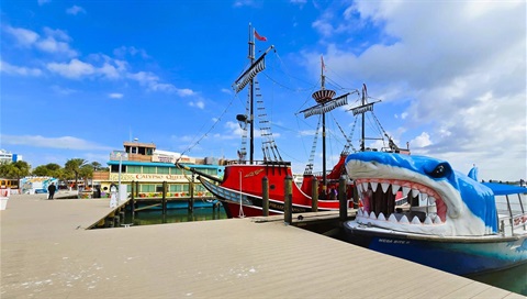 beach marina with pirate ship and boat with shark head on front