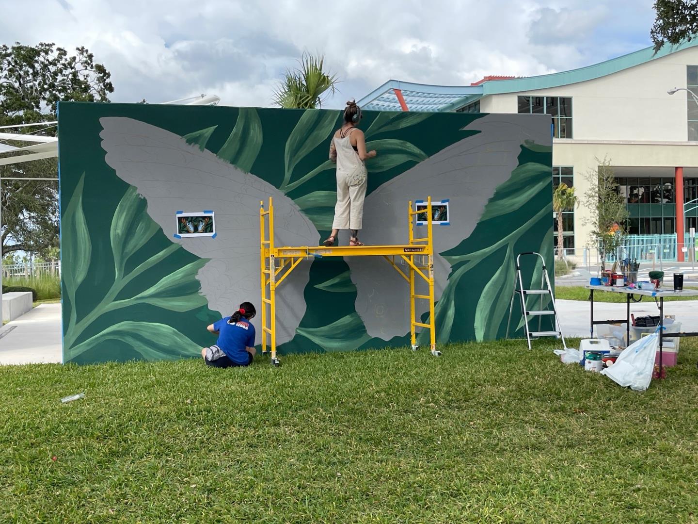 Image of two artists working on butterfly mural