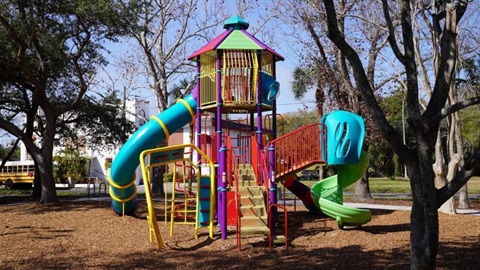 Colorful playground slide in tree lined park.